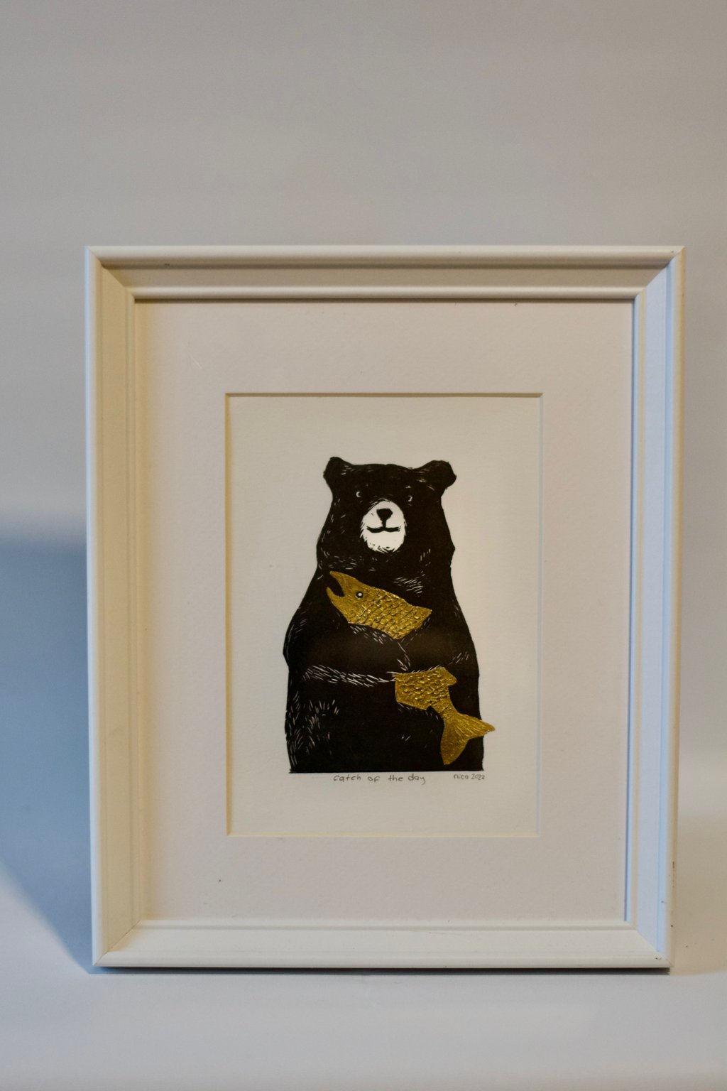 A photo of a painting of a happy black bear with its arms around a large golden fish