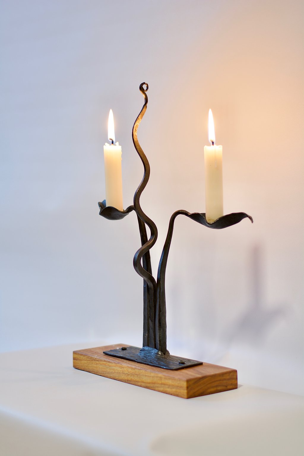 A photo of a wrought iron candle holder with two lit candles