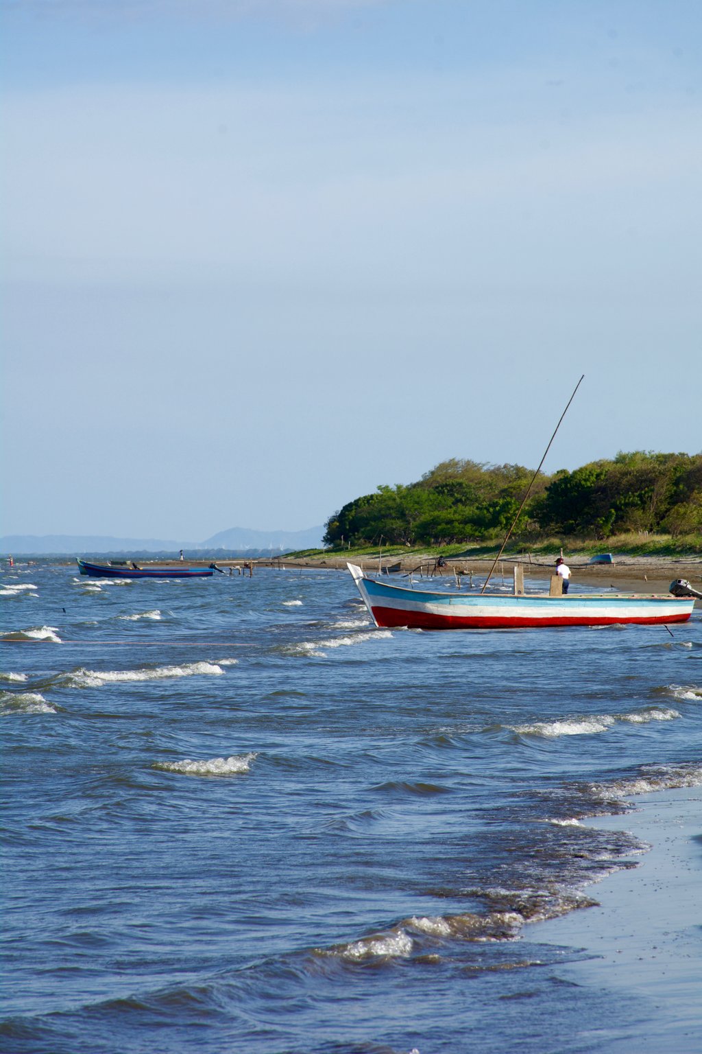 A photo of a red boat just offshore in wavy waters